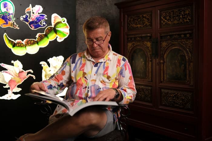 Cengiz Özek in his workshop with translucent Karagöz figures lit on the wall behind him