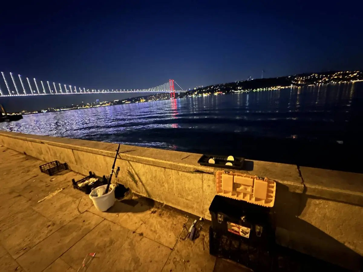 The Bosphorus Bridge lit up at night, seen from the fishing spot