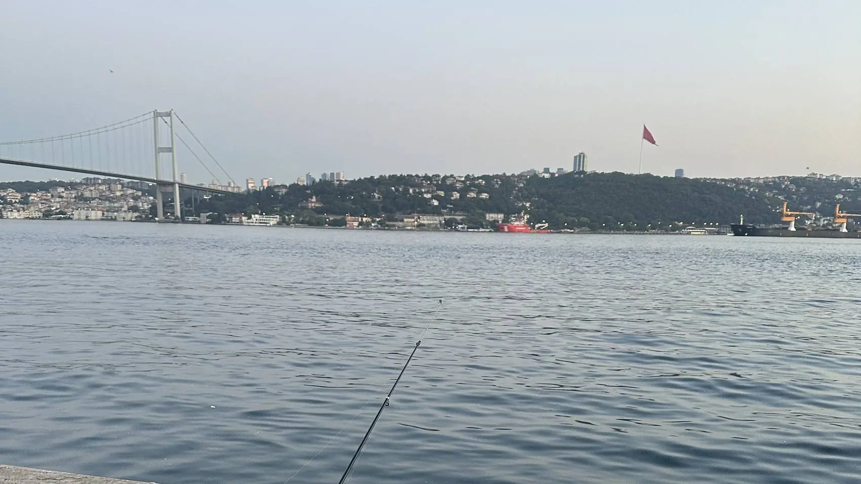 Fishing rod on the Bosphorus quay with the bridge in the distance